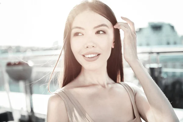 Senhora elegante e bonita sorrindo e segurando a mão perto da cabeça . — Fotografia de Stock