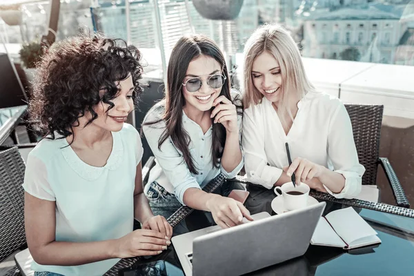 Friendly pretty girls using the laptop and smiling. — Stock Photo, Image