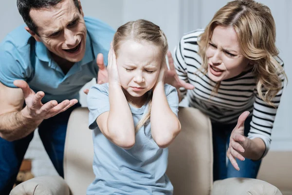 Fille sans sourire et ses parents criant à elle — Photo