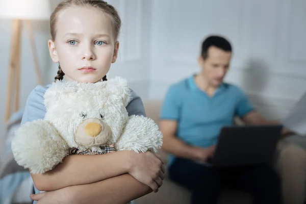 Miserable child standing with her toy — Stockfoto