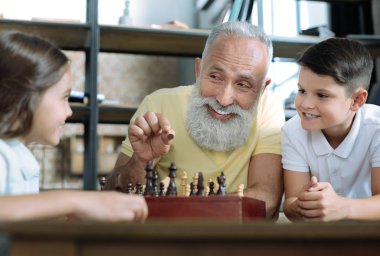 Komik dedesi satranç çocuklarla oynarken gülümseyen