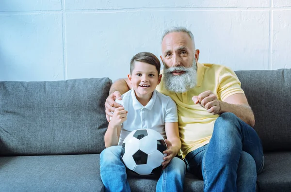 Upphetsad barnbarn och senior man titta på fotboll match — Stockfoto