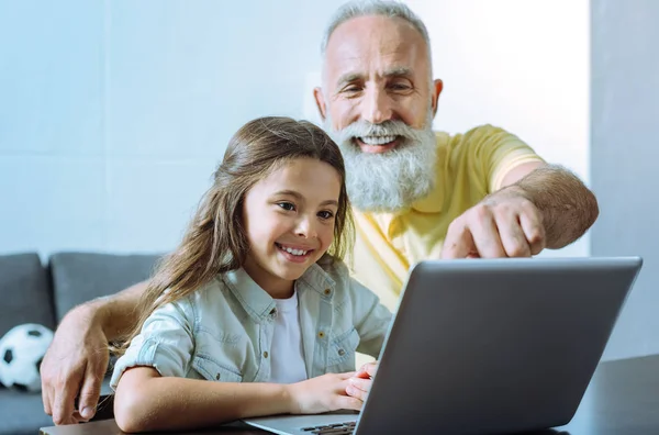Lleno de felicidad abuelo y chica usando el ordenador portátil juntos — Foto de Stock