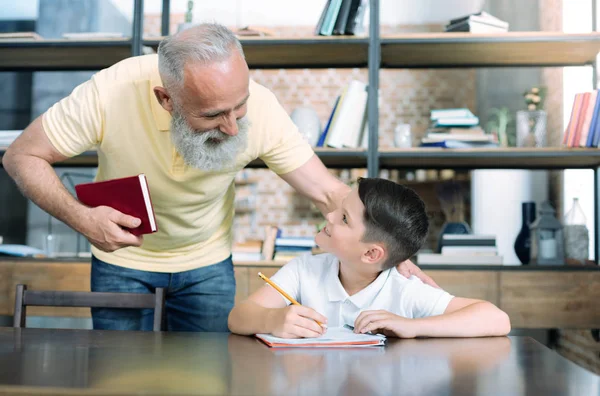 Заботливые бабушка и дедушка помогают ребенку с домашним заданием — стоковое фото