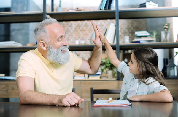Милая девушка и ее дедушка дают пять после выполнения домашней работы — стоковое фото