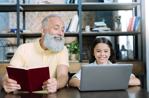 El abuelo curioso que mira el portátil de la nieta con el interés — Foto de Stock