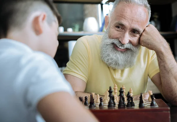 Alegre abuelo radiante mientras juega al ajedrez con el niño — Foto de Stock