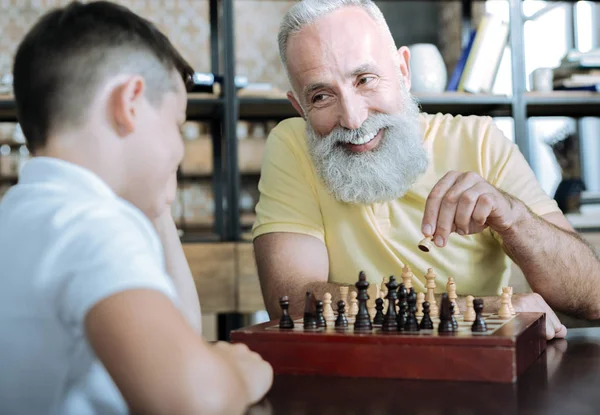 Задумчивый дедушка учит детей шахматной игре — стоковое фото