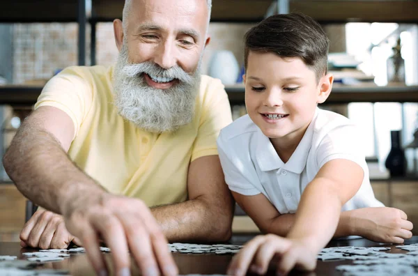 Kid ja isoisä koota palapeli — kuvapankkivalokuva