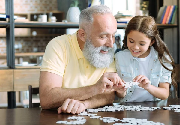 Grandfather and girl chatting while playing jigsaw puzzle — Stock Photo, Image