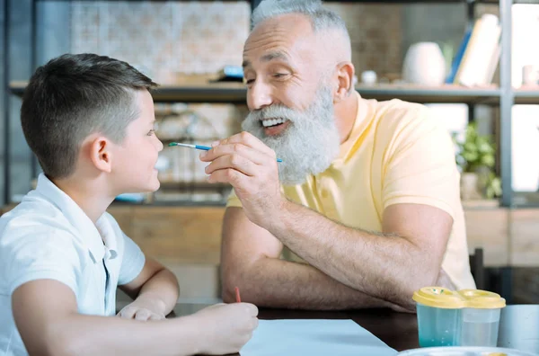 Alegre abuelo y niño bromeando mientras pintan en casa — Foto de Stock