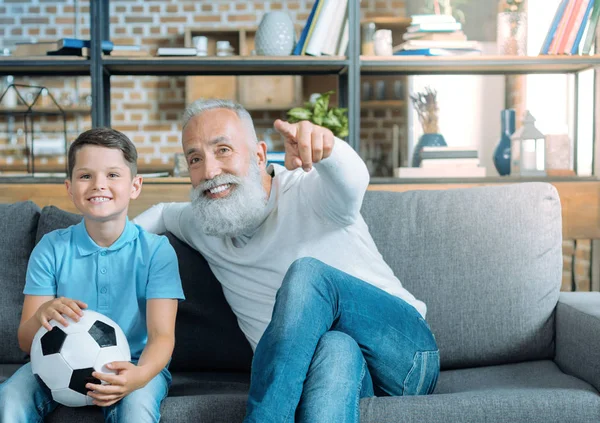 Hombre de edad avanzada de mente positiva y nieto viendo fútbol juntos —  Fotos de Stock