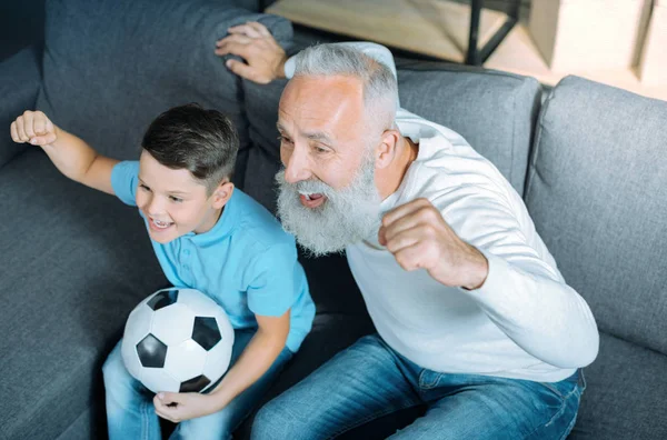 Alegre abuelo y niño viendo partido de fútbol juntos — Foto de Stock