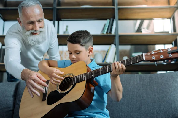 Mindful caballero mayor enseñando nieto tocar la guitarra — Foto de Stock