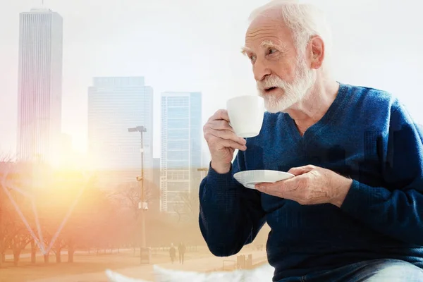 Viejo barbudo mirando a la distancia mientras bebe café — Foto de Stock