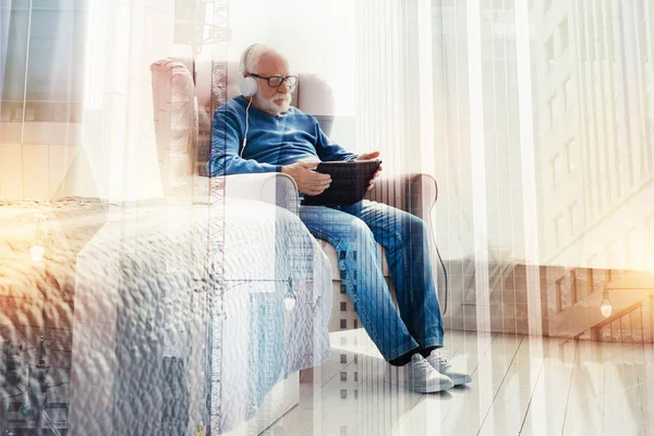 Kluger alter Mann sitzt mit Tablet und hört Musik — Stockfoto