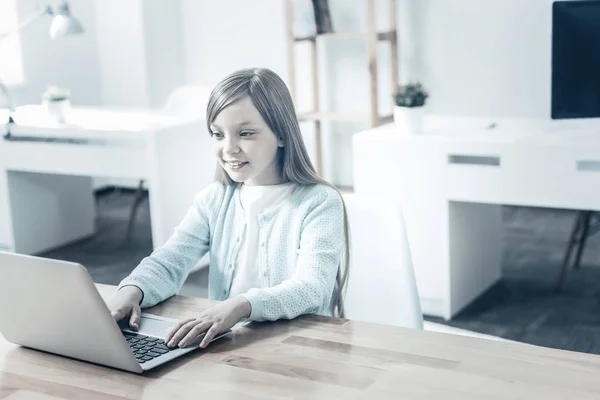 Alegre niña preadolescente sonriendo mientras trabaja en el ordenador portátil —  Fotos de Stock