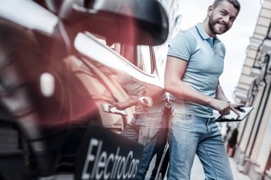 Modern elektrikli otomobil eğilerek tablet ile kendine güvenen genç adam