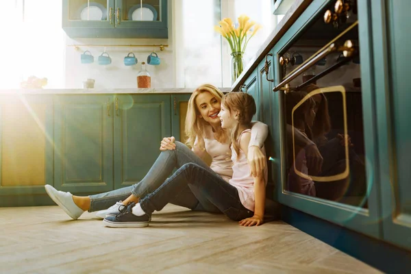 Rozjaření matka a dcera sedí na podlaze — Stock fotografie