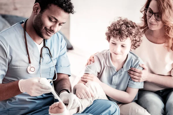 Mindful doctor bandaging foot of teen patient