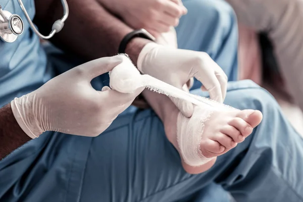 Scaled up look on physician bandaging foot — Stock Photo, Image