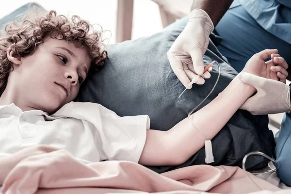 Ragazzo preoccupato guardando il medico che mette la flebo in ospedale — Foto Stock