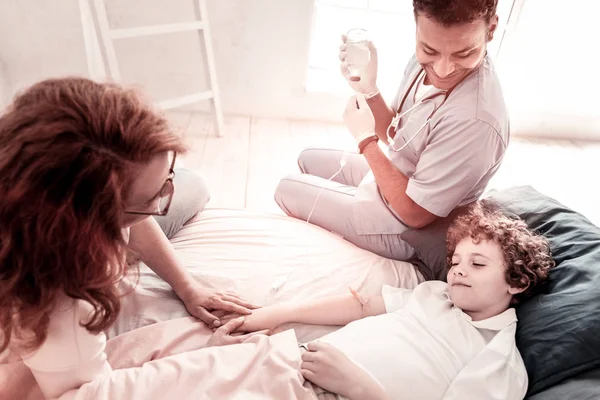 Madre consapevole e medico tirando su povero adolescente malato — Foto Stock