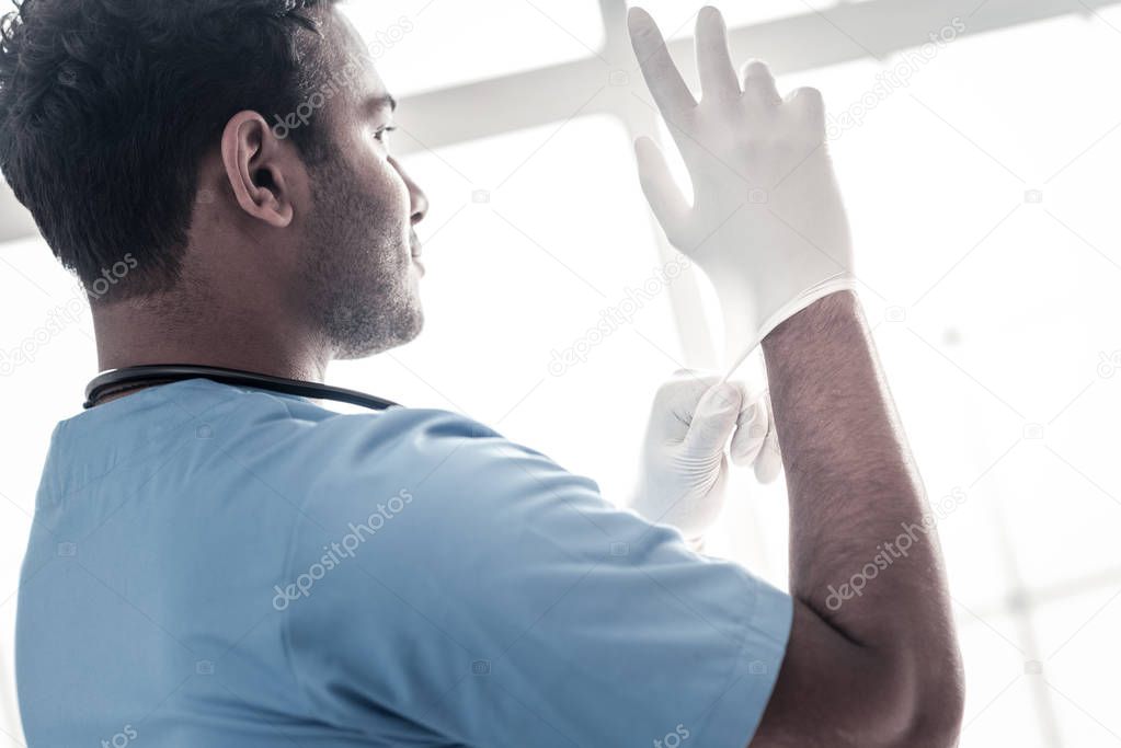 Smart millennial doctor putting on his gloves
