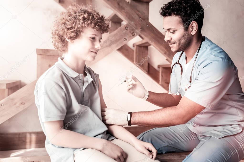 Male doctor vaccinating relaxed teen boy