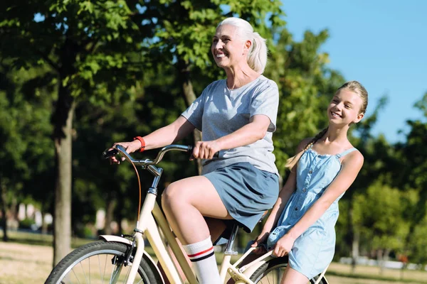 Mujer anciana positiva montando una bicicleta — Foto de Stock
