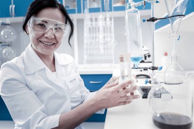 Test tüpleri tutarken gülümseyen neşeli kadın bilim adamı