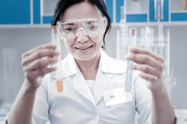Trabalhador de laboratório com mentalidade positiva examinando tubos de ensaio com líquidos — Fotografia de Stock