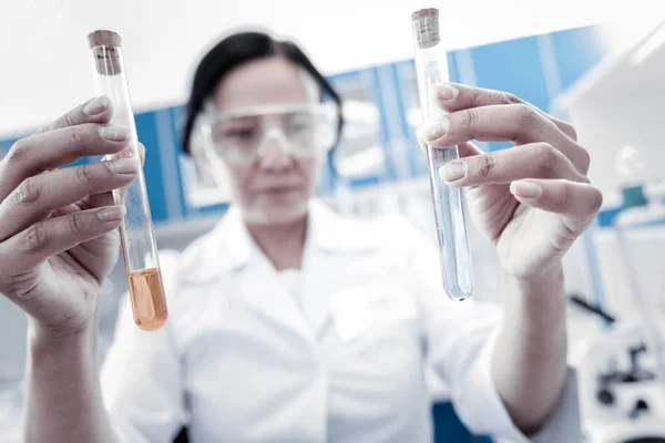 Professionista femminile che confronta liquidi chimici in provette — Foto Stock