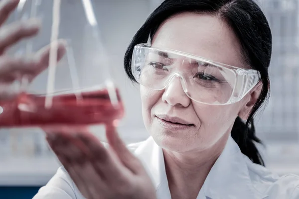 Profissional focado feminino examinando líquido químico em laboratório — Fotografia de Stock