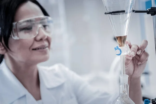 Cientista alegre que regula utensílios de vidro de laboratório fixados em suporte de metal — Fotografia de Stock