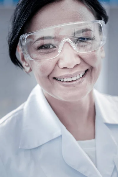 Beautiful woman wearing safety glasses smiling into camera