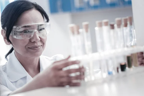 Satisfaz a cientista feminina examinando tubos de ensaio com líquidos — Fotografia de Stock