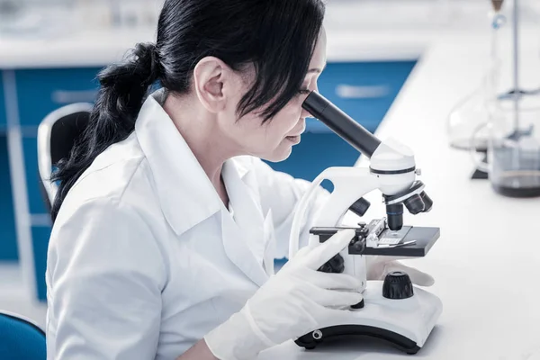 Cientista concentrado que examina a amostra ao microscópio — Fotografia de Stock