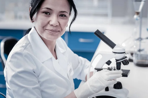 Smiling mature lady posing for camera while working in laboratory
