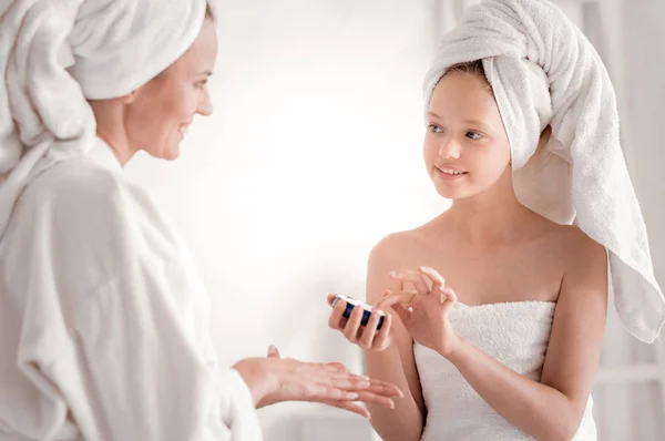 Nice young girl learning how to apply cream — Stock Photo, Image