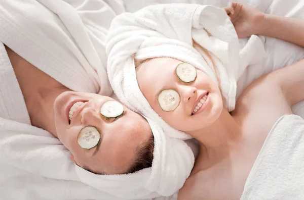 Happy nice mother and daughter doing a cucumber mask