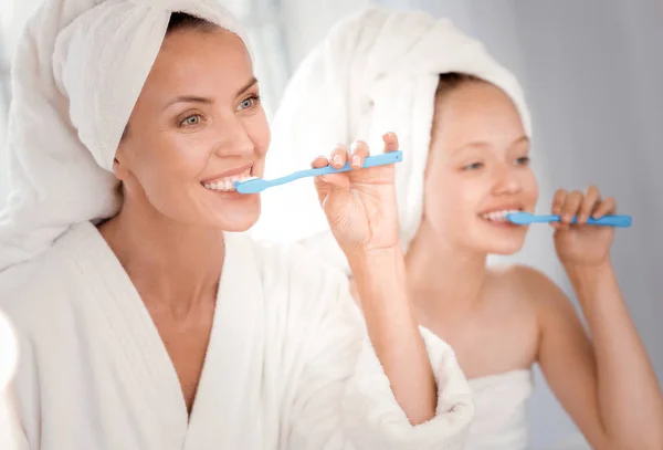 Deleitado agradable mujer cepillarse los dientes junto con su hija — Foto de Stock