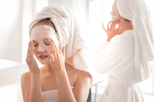 Beautiful young girl applying facial mask — Stock Photo, Image
