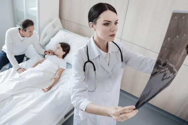 Médico sério examinando tomografias computadorizadas de menina — Fotografia de Stock