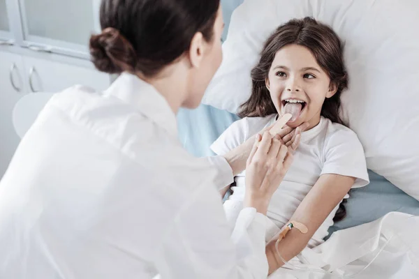 Médico femenino comprobando garganta con palo de madera desechable — Foto de Stock