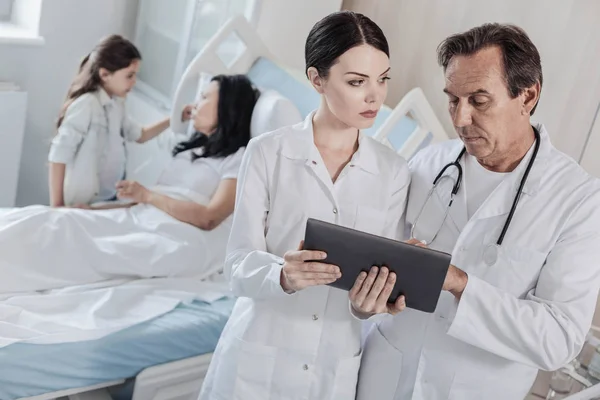 Serious medical worker consulting over female patient — Stock Photo, Image