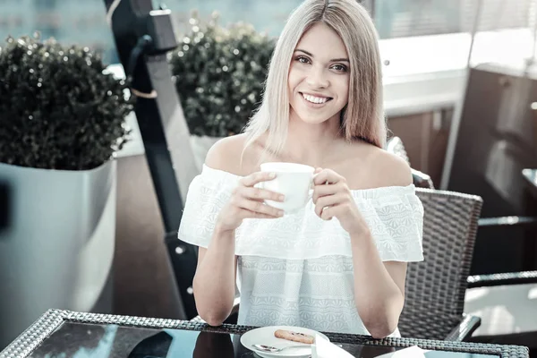 Mujer hermosa positiva sosteniendo una taza de café — Foto de Stock