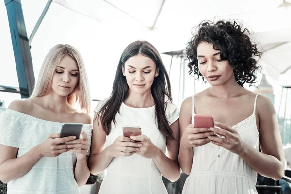 Jovens mulheres agradáveis usando seus smartphones — Fotografia de Stock
