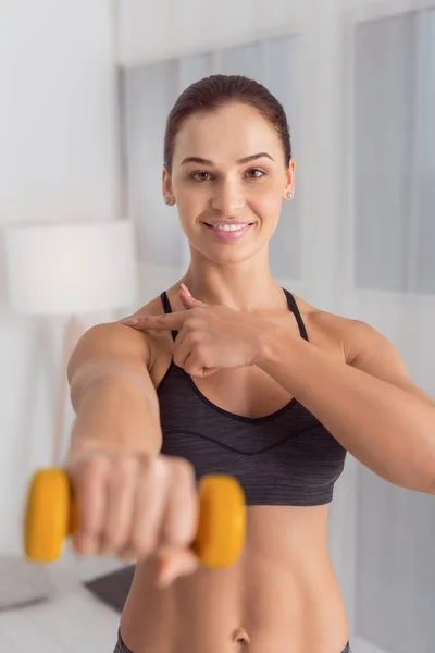 Smiling woman holding a hand weight in front of her — Stock Photo, Image