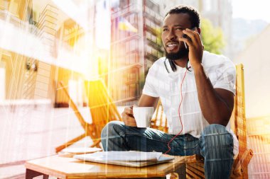 Meşgul öğrenci süre konuşmak bir telefon sahip ve kahve içme çatık